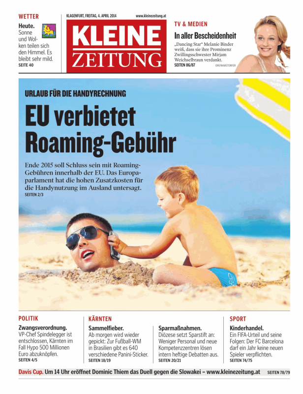 Ein Mann im Sand telefoniert, während ein Kind daneben sitzt.