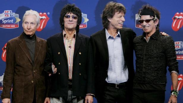 Die Rolling Stones posieren vor einem blauen Hintergrund mit ihrem Logo.