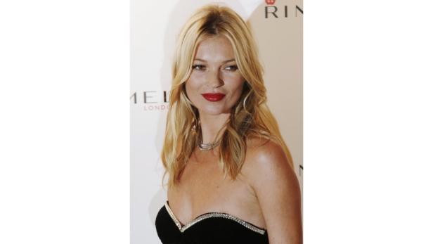 Kate Moss mit blonden Haaren und rotem Lippenstift auf einer Veranstaltung.