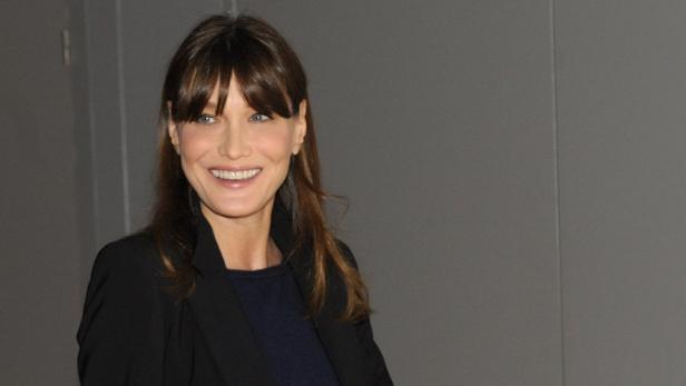 Carla Bruni lächelt in einem schwarzen Blazer.