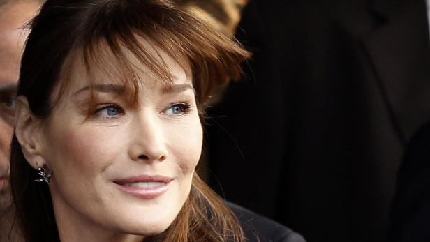 Ein Porträt von Carla Bruni mit braunen Haaren und hellblauen Augen.
