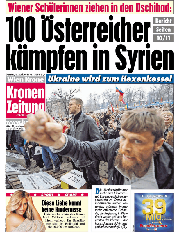 Eine Menschenmenge demonstriert auf der Straße, einige schwenken Fahnen.