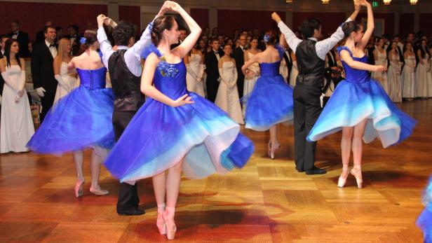 Tänzerinnen in blauen Kleidern und Spitzenschuhen führen eine Ballettvorstellung auf einem Ball auf.
