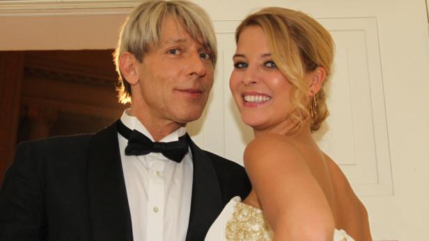 Ein Mann im Smoking und eine Frau im Abendkleid lächeln in die Kamera.