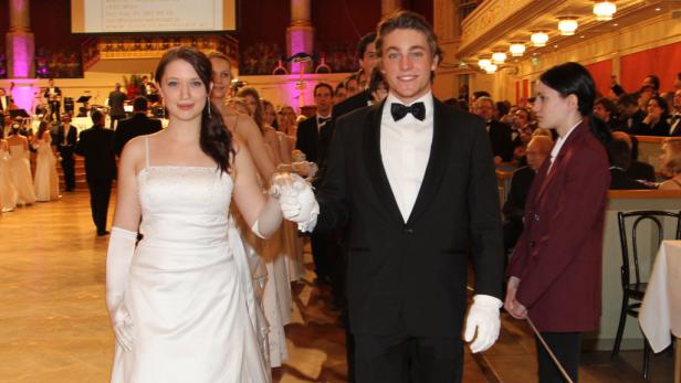 Ein junges Paar in Ballkleidung führt eine Polonaise an.