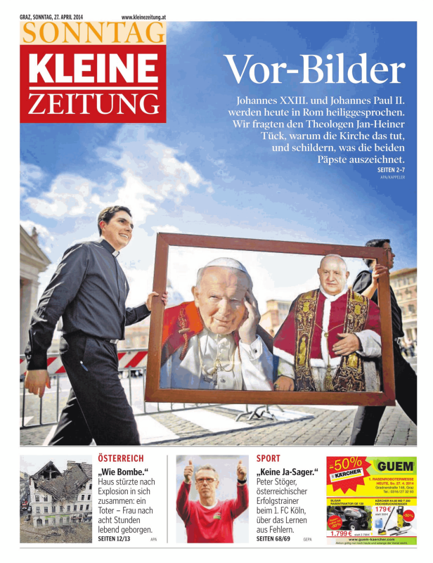 Ein Priester trägt ein gerahmtes Bild von Johannes Paul II. und Johannes XXIII..