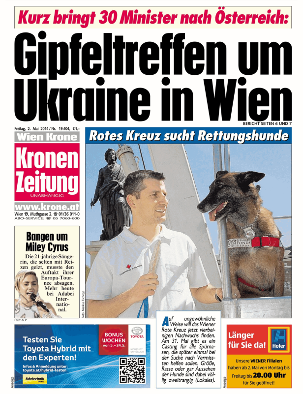 Ein Mann vom Roten Kreuz mit einem Rettungshund vor einem Denkmal in Wien.
