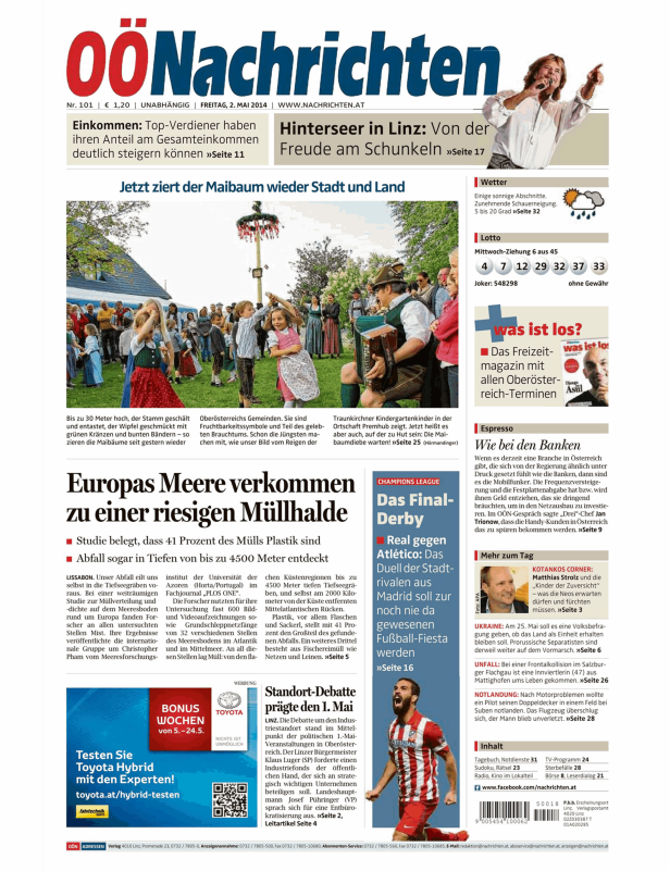 Eine Gruppe von Menschen feiert um einen Maibaum auf einer Wiese.