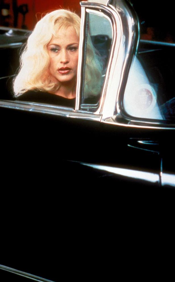 Eine blonde Frau sitzt in einem schwarzen Auto.