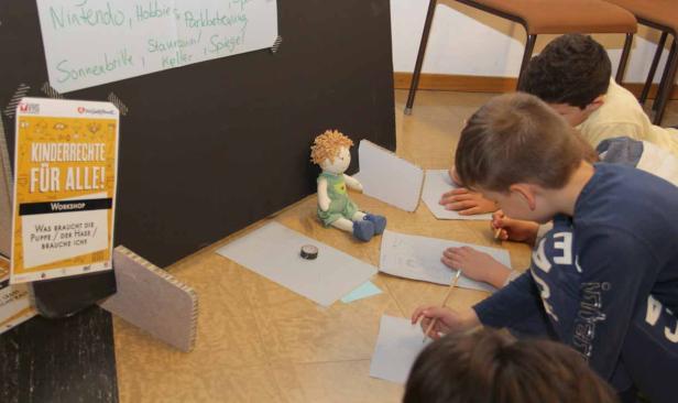 Kinder zeichnen auf dem Boden während eines Workshops zum Thema Kinderrechte.