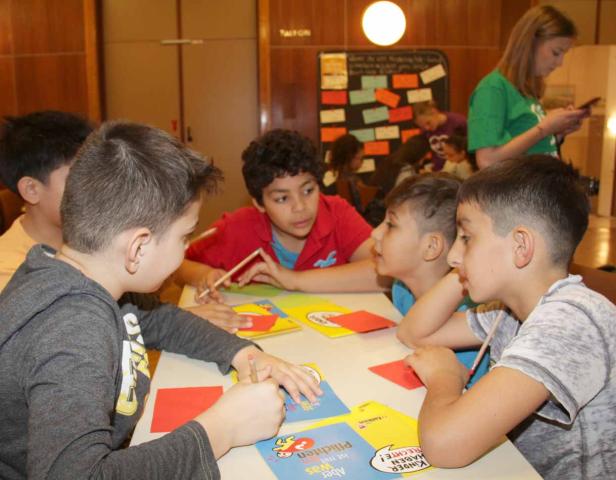Eine Gruppe Kinder sitzt an einem Tisch und arbeitet an einem Projekt.