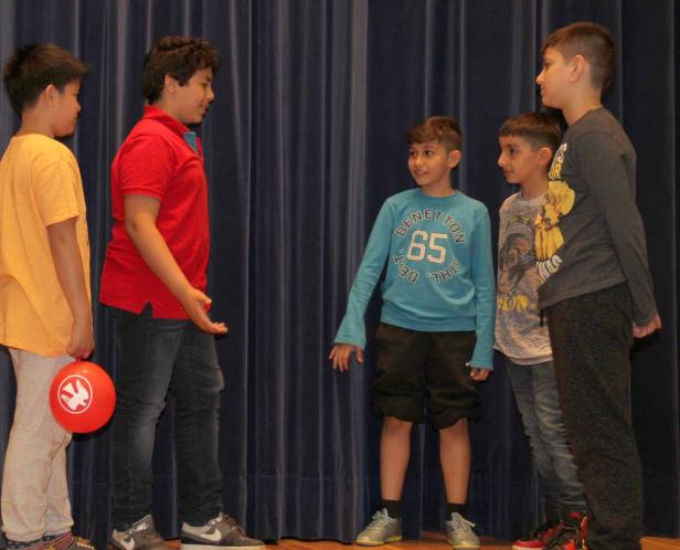 Fünf Jungen stehen vor einem dunklen Vorhang.