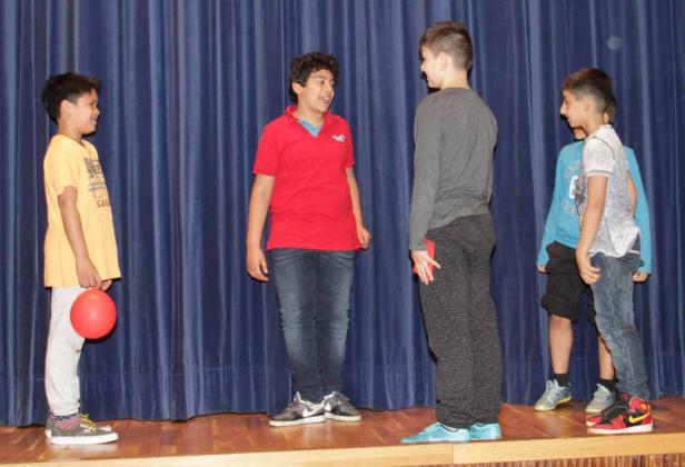 Vier Jungen stehen auf einer Bühne vor einem blauen Vorhang.