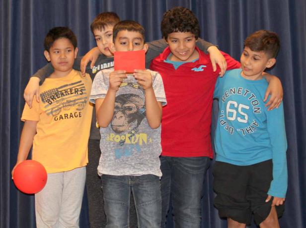 Eine Gruppe von fünf Jungen posiert vor einem blauen Vorhang.