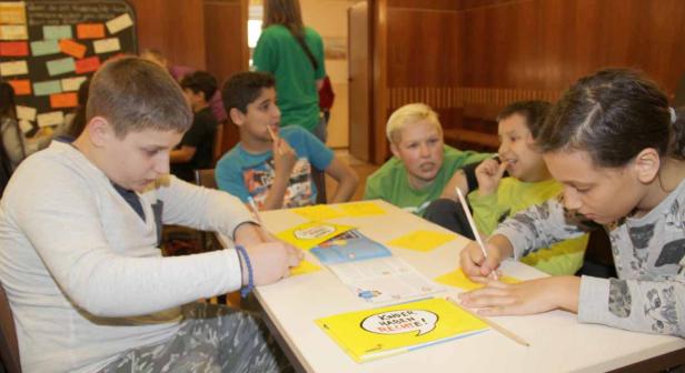 Eine Gruppe von Kindern sitzt an einem Tisch und arbeitet an einem Projekt zum Thema Kinderrechte.