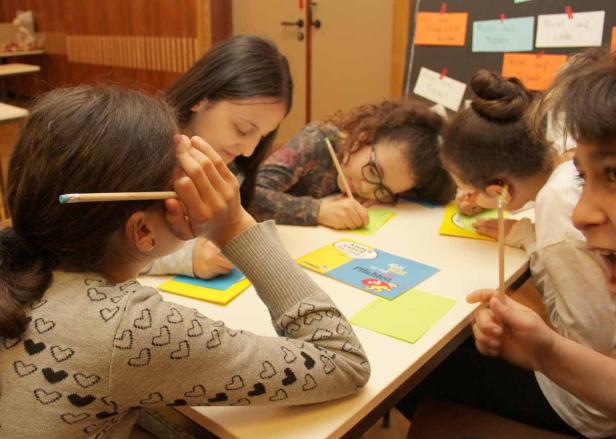 Eine Gruppe von Kindern sitzt an einem Tisch und arbeitet an einer Aufgabe.