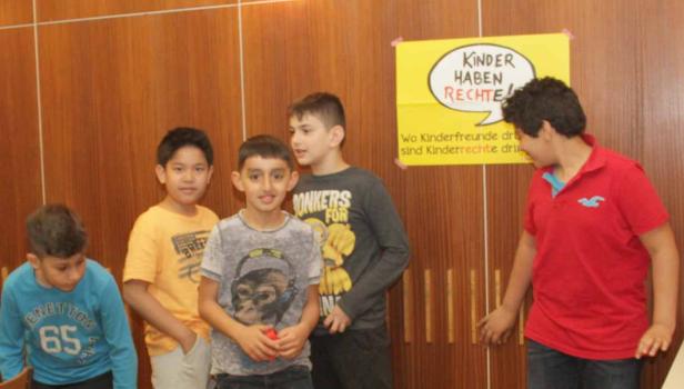 Fünf Jungen stehen vor einem Plakat mit der Aufschrift „Kinder haben Rechte!“.