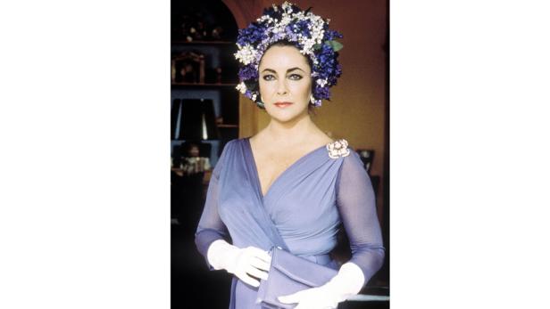 Elizabeth Taylor mit einem Blumenkranz und einem lila Kleid.