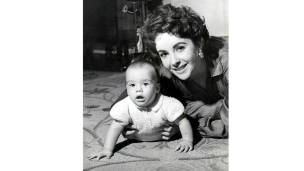 Elizabeth Taylor mit ihrem Baby auf einem Teppich.