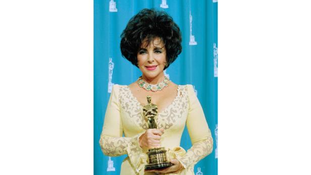 Elizabeth Taylor hält eine Oscar-Statue in den Händen.