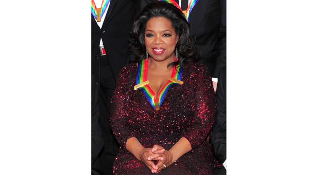 Oprah Winfrey trägt ein rotes, paillettenbesetztes Kleid und eine Ehrenmedaille.