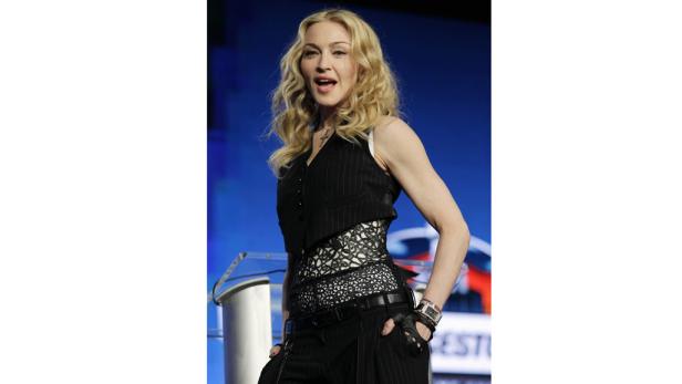 Madonna in einem schwarzen Hosenanzug mit Weste auf einer Bühne.