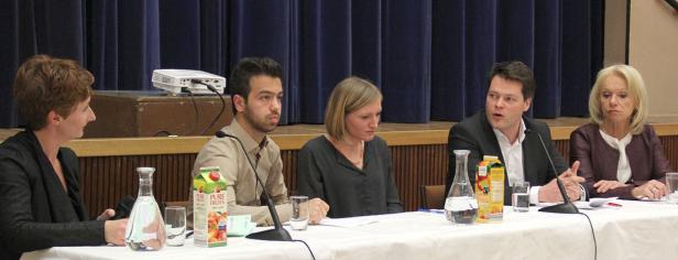 Fünf Personen sitzen an einem Tisch während einer Podiumsdiskussion.