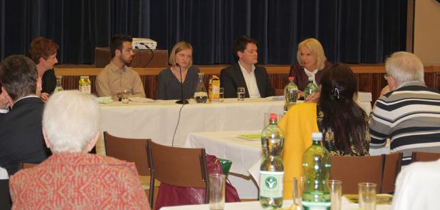 Eine Podiumsdiskussion mit mehreren Personen an einem Tisch vor Publikum.