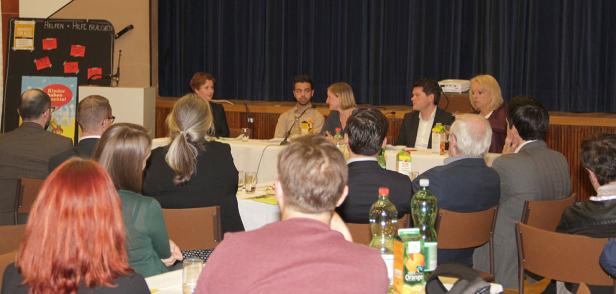 Eine Podiumsdiskussion mit mehreren Personen vor einem Publikum.