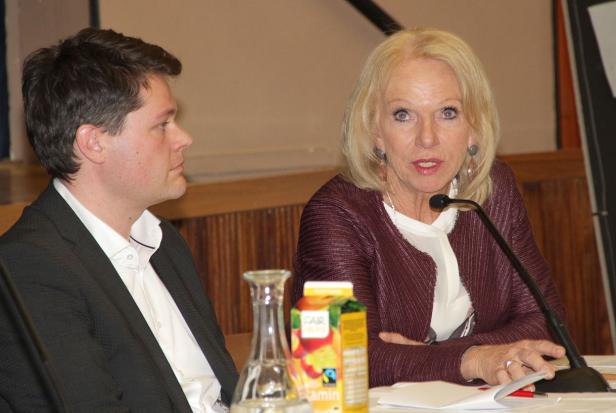 Eine Frau spricht am Mikrofon, während ein Mann ihr aufmerksam zuhört.