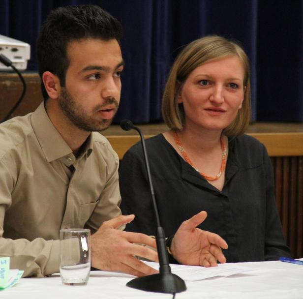 Ein Mann und eine Frau sitzen an einem Tisch und sprechen in Mikrofone.