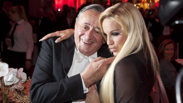 Ein älterer Mann im Smoking umarmt eine blonde Frau.