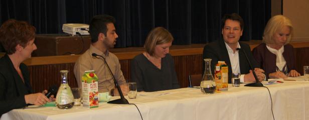 Fünf Personen sitzen an einem Tisch während einer Podiumsdiskussion.