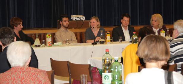 Eine Podiumsdiskussion mit mehreren Personen an einem Tisch vor Publikum.