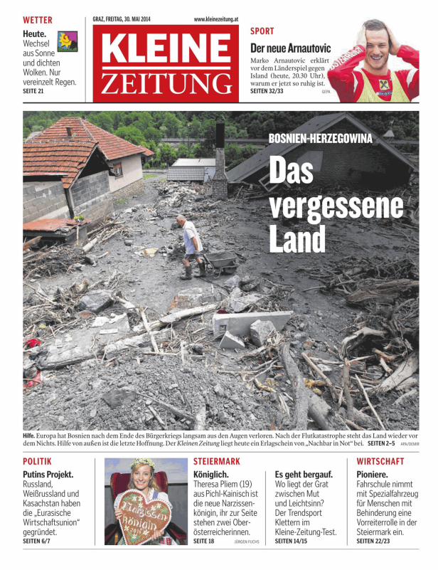 Ein Mann schiebt eine Schubkarre durch eine überflutete Landschaft in Bosnien-Herzegowina.