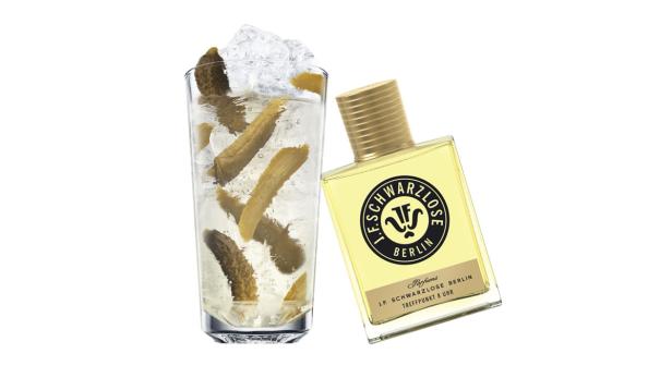 Ein Glas mit Eiswasser und Gurken neben einem Parfüm von J.F. Schwarzlose Berlin.
