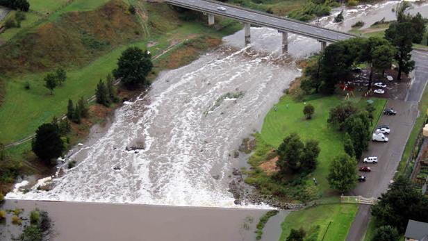 Ein Fluss tritt über die Ufer und überflutet das umliegende Land unterhalb einer Brücke.