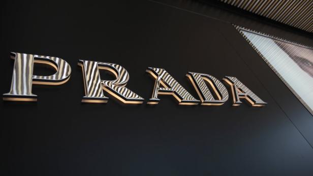 Das Prada-Logo an einer dunklen Wand.