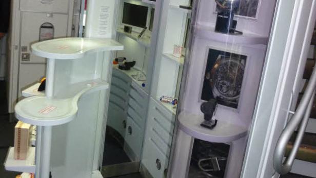 Innenansicht eines Flugzeugs mit Servierwagen und Ausstellungsstücken.