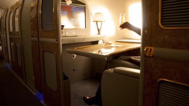 Eine Person genießt ein Glas Champagner in der luxuriösen Kabine eines Flugzeugs.