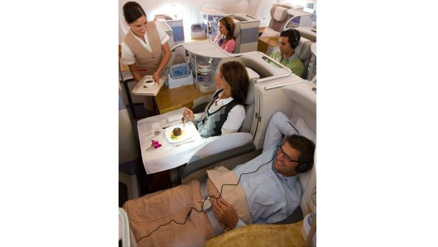 Ein Flugbegleiter serviert einem Passagier in der Business Class Kaffee.