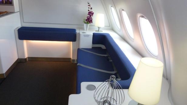 Ein blauer Sitzbereich mit Lampe und Fenster in einem Flugzeug.