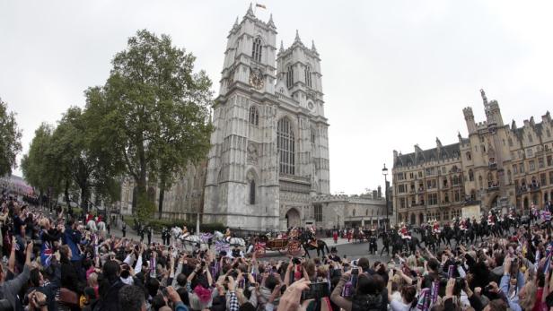 Eine Menschenmenge beobachtet eine Pferdekutsche vor Westminster Abbey in London.