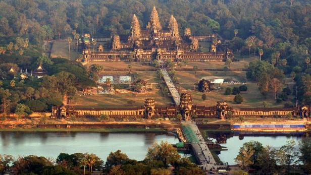 Luftaufnahme von Angkor Wat, einem Tempelkomplex in Kambodscha, umgeben von Bäumen und einem See.