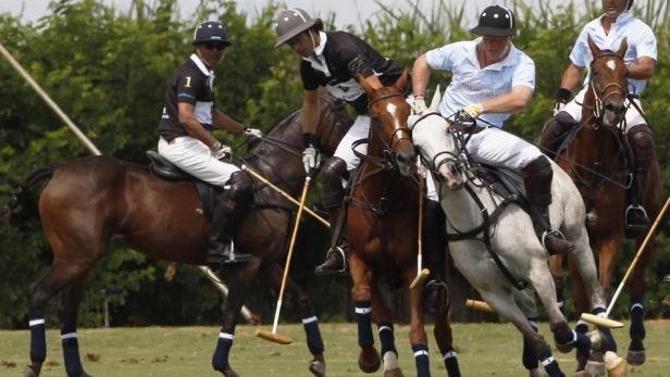 Mehrere Polospieler reiten auf ihren Pferden während eines Spiels.
