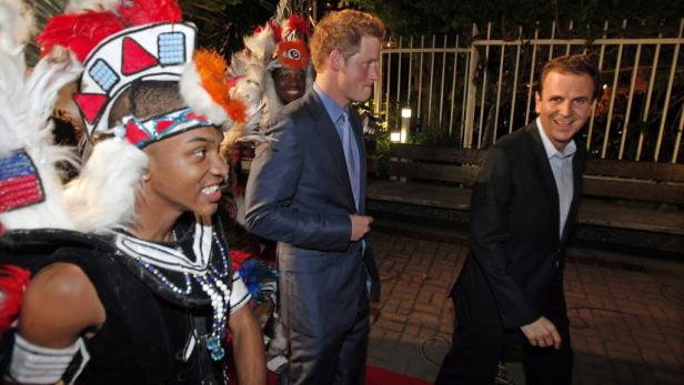 Prinz Harry und zwei Männer, einer davon in traditioneller Zulu-Kleidung.