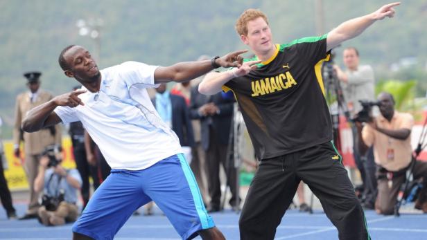 Usain Bolt und Prinz Harry posieren auf einer blauen Laufbahn.