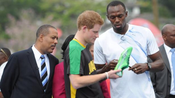 Usain Bolt signiert einen grünen Schuh für Prinz Harry.