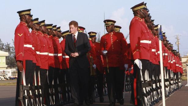 Prinz Harry geht an einer Ehrenformation in roter Uniform vorbei.