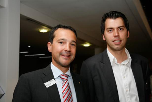 Zwei Männer in Anzügen posieren für ein Foto.